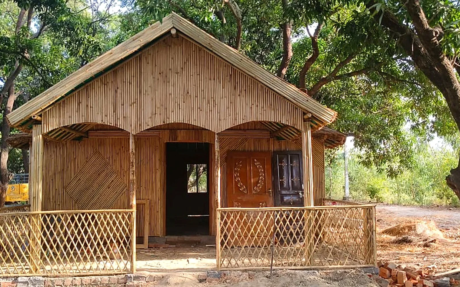 Bamboo cottage with a shaded veranda beneath leafy trees
