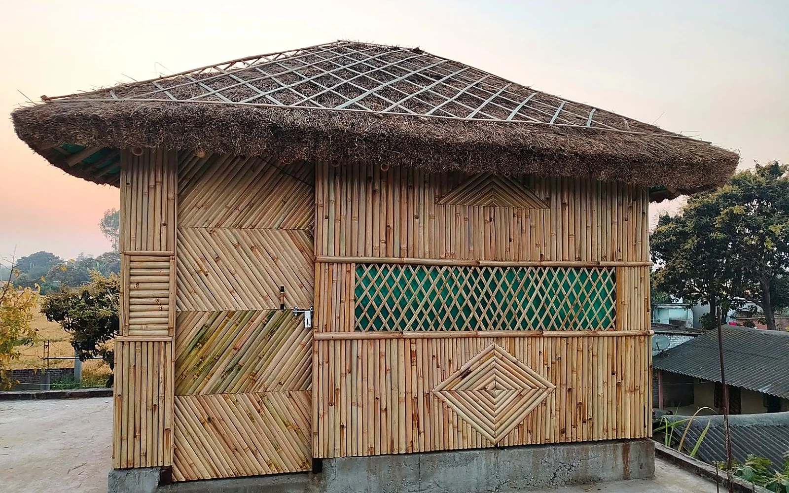 Bamboo cottage exterior at dusk with a warm interior glow