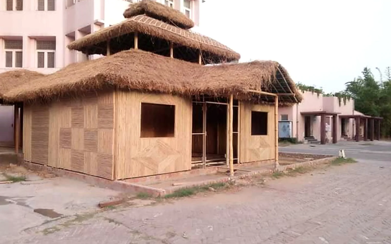 Wide bamboo cottage with layered thatched roofs and a front veranda